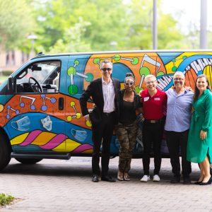 Kathrine G McGovern College of the Arts employees pose in front of the new van. NOAH is proud to partner with KGMCA!
