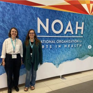 Two people pose in front of the NOAH backdrop